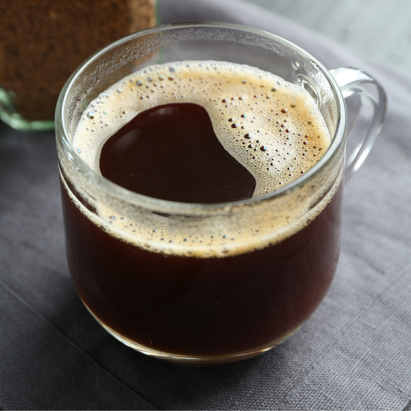 A clear glass cup filled with freshly mixed instant coffee