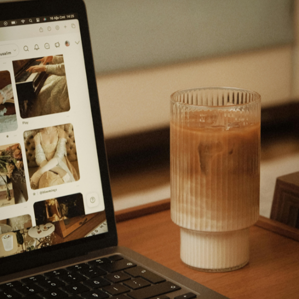 Tall glass of vegan Vietnamese iced coffee sitting next to an open laptop on a wooden desk